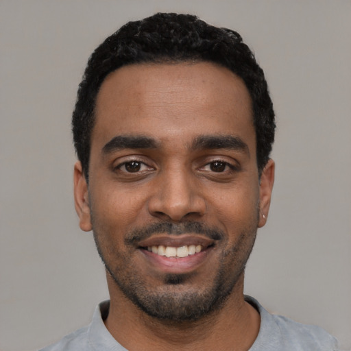 Joyful black young-adult male with short  black hair and brown eyes