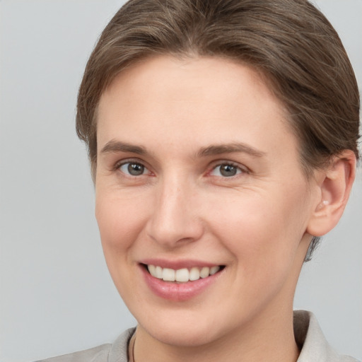 Joyful white young-adult female with short  brown hair and grey eyes