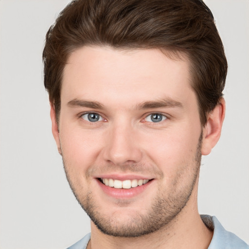 Joyful white young-adult male with short  brown hair and grey eyes