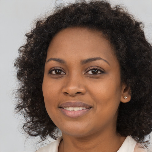 Joyful black young-adult female with long  brown hair and brown eyes