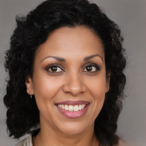 Joyful black young-adult female with long  brown hair and brown eyes