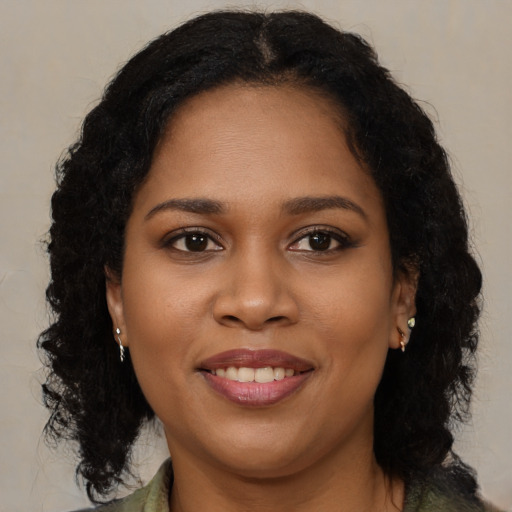 Joyful black young-adult female with long  brown hair and brown eyes