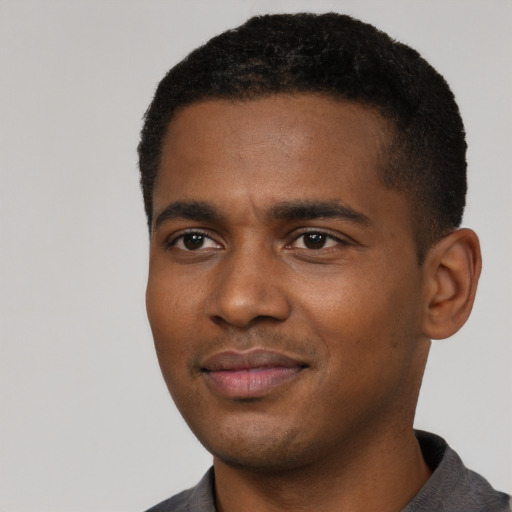 Joyful black young-adult male with short  black hair and brown eyes