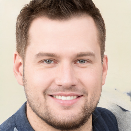 Joyful white young-adult male with short  brown hair and grey eyes