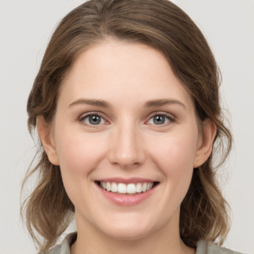 Joyful white young-adult female with medium  brown hair and grey eyes