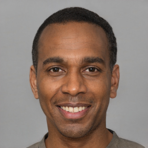 Joyful black young-adult male with short  black hair and brown eyes