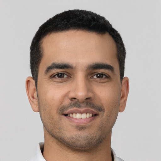 Joyful latino young-adult male with short  black hair and brown eyes