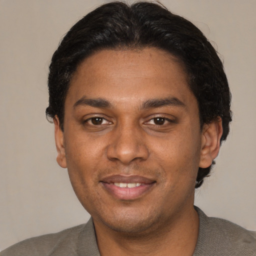 Joyful black young-adult male with short  black hair and brown eyes
