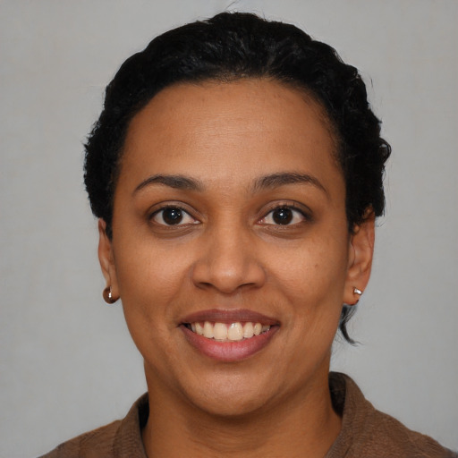 Joyful black young-adult female with short  black hair and brown eyes