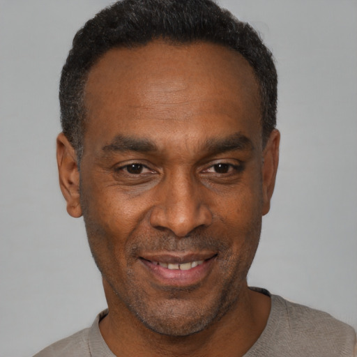 Joyful black adult male with short  black hair and brown eyes