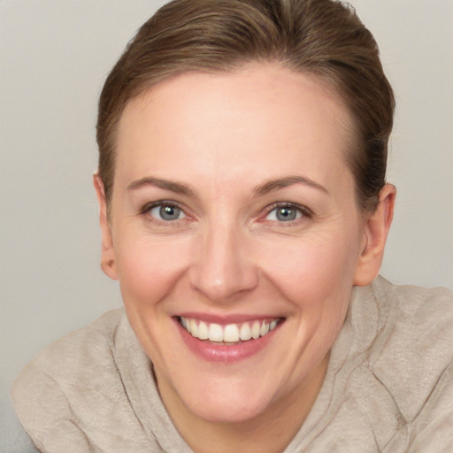 Joyful white adult female with short  brown hair and blue eyes