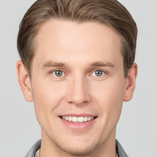 Joyful white young-adult male with short  brown hair and grey eyes