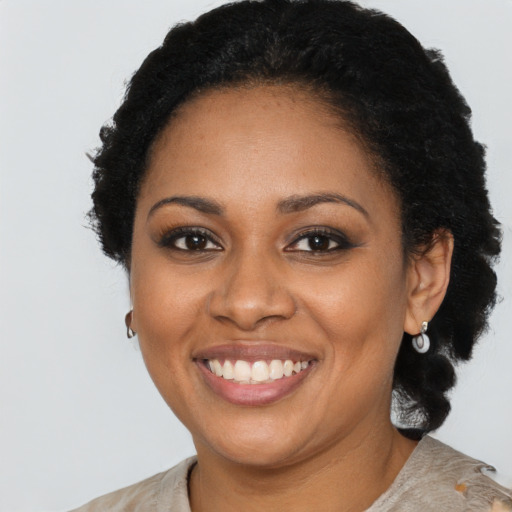 Joyful black young-adult female with long  brown hair and brown eyes