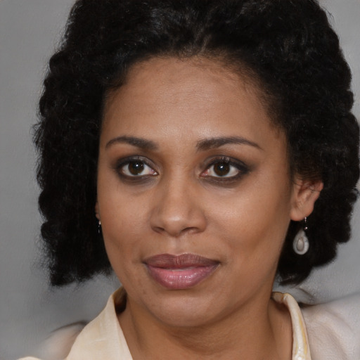 Joyful black young-adult female with long  brown hair and brown eyes