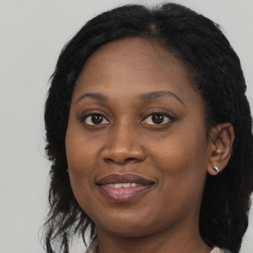 Joyful black young-adult female with long  black hair and brown eyes
