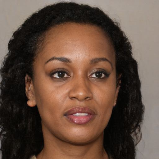 Joyful black young-adult female with long  brown hair and brown eyes