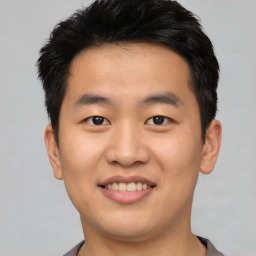 Joyful asian young-adult male with short  black hair and brown eyes