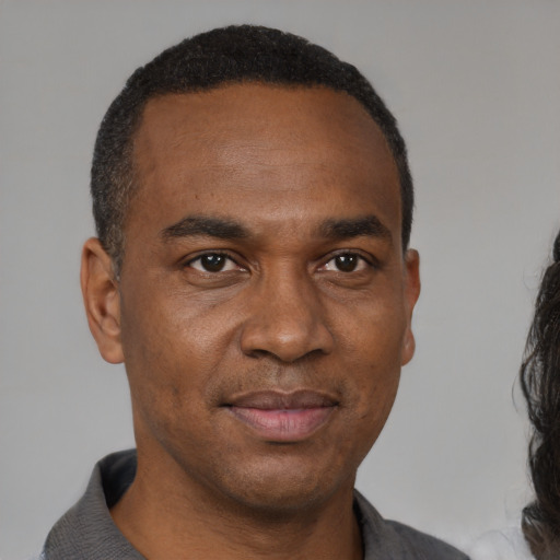 Joyful black adult male with short  black hair and brown eyes