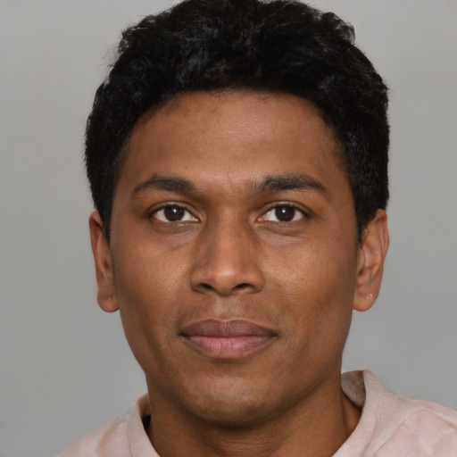 Joyful black young-adult male with short  black hair and brown eyes