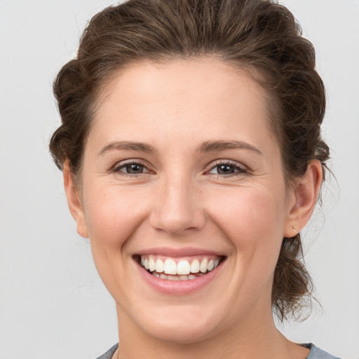 Joyful white young-adult female with medium  brown hair and grey eyes