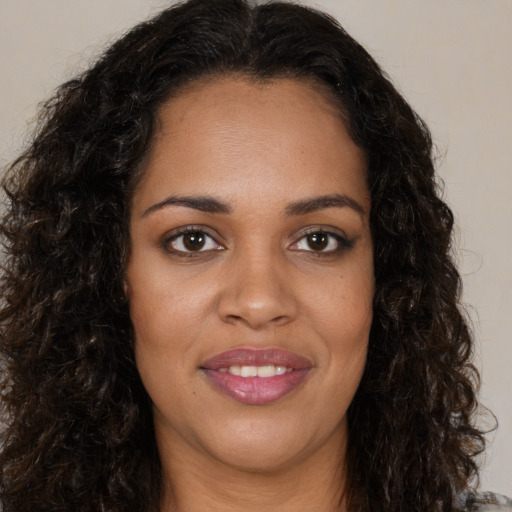 Joyful black young-adult female with long  brown hair and brown eyes