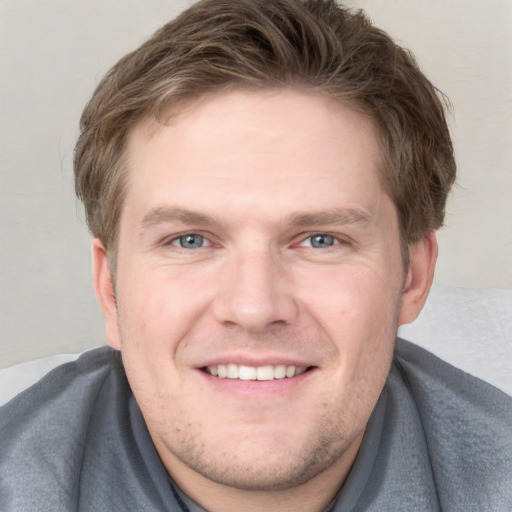 Joyful white young-adult male with short  brown hair and blue eyes