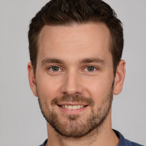 Joyful white young-adult male with short  brown hair and grey eyes