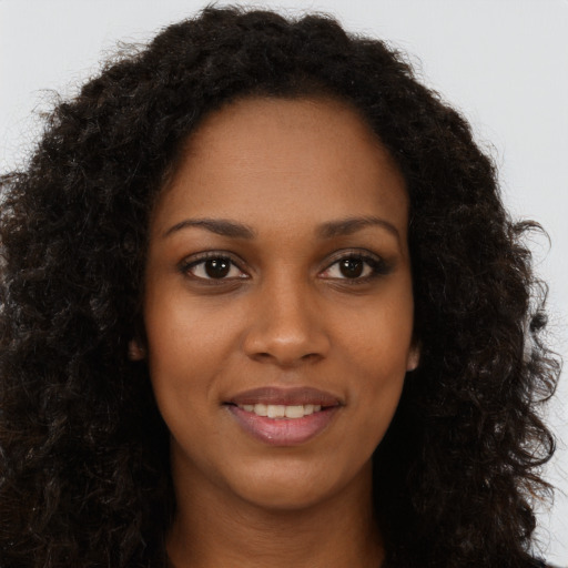 Joyful black young-adult female with long  brown hair and brown eyes