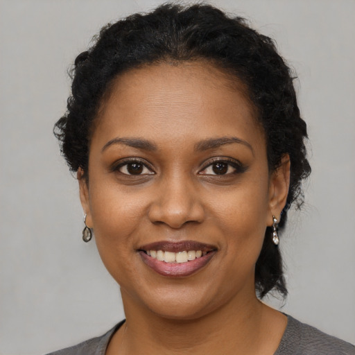 Joyful black young-adult female with short  black hair and brown eyes