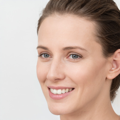 Joyful white young-adult female with medium  brown hair and grey eyes