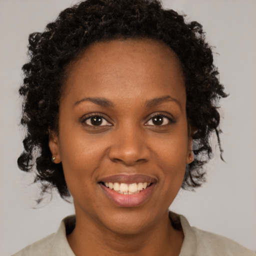 Joyful black young-adult female with short  brown hair and brown eyes