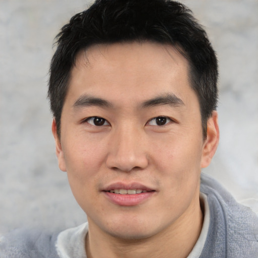 Joyful asian young-adult male with short  black hair and brown eyes