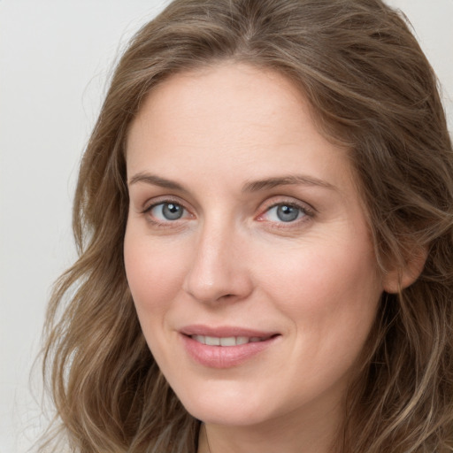 Joyful white young-adult female with long  brown hair and blue eyes