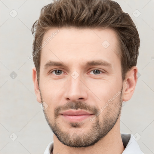 Joyful white young-adult male with short  brown hair and grey eyes