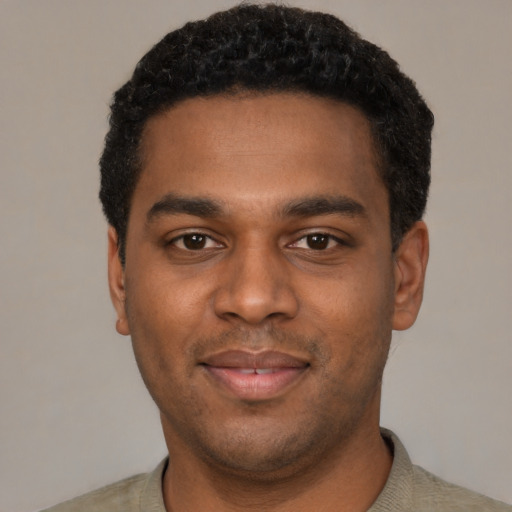 Joyful black young-adult male with short  black hair and brown eyes