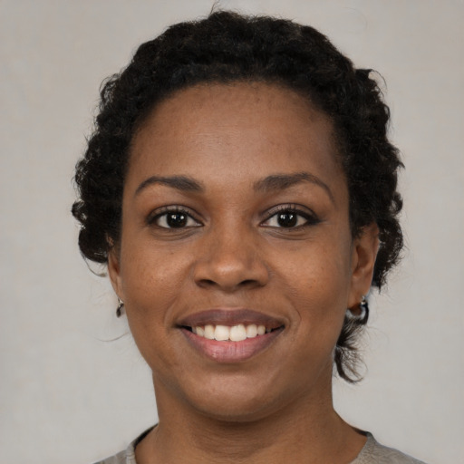 Joyful black young-adult female with short  brown hair and brown eyes