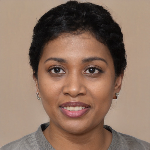 Joyful black young-adult female with short  black hair and brown eyes