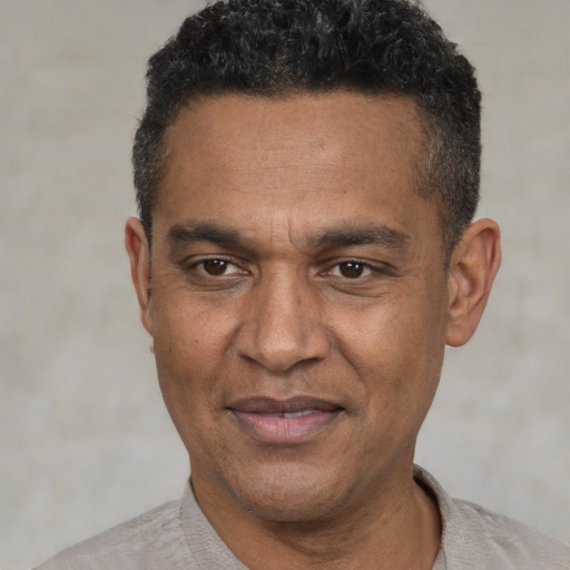 Joyful black adult male with short  black hair and brown eyes