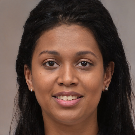Joyful black young-adult female with long  brown hair and brown eyes