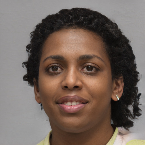 Joyful black young-adult female with long  black hair and brown eyes