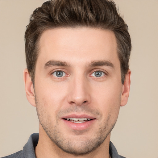 Joyful white young-adult male with short  brown hair and grey eyes