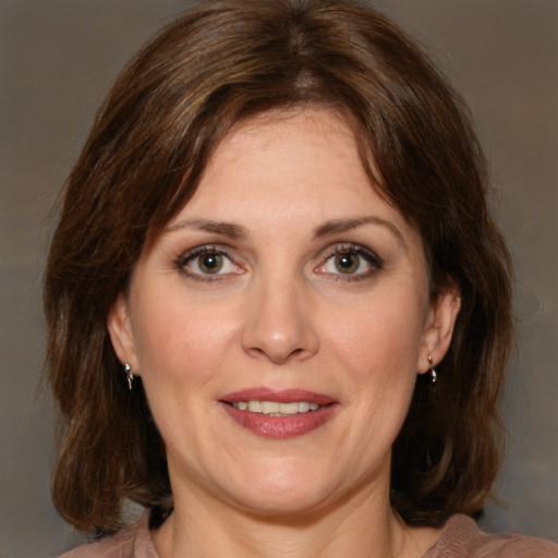 Joyful white adult female with medium  brown hair and green eyes