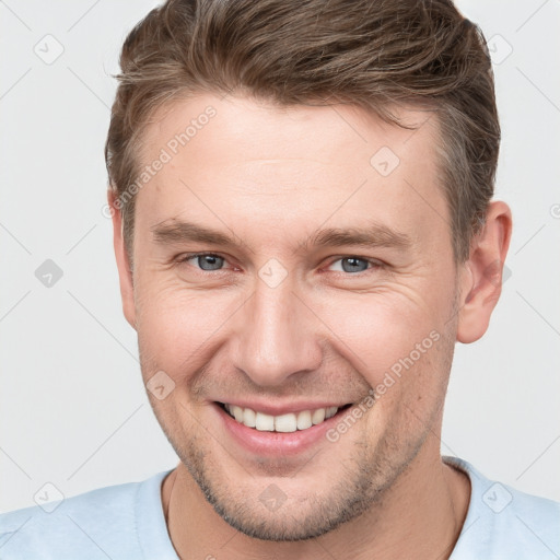 Joyful white young-adult male with short  brown hair and grey eyes