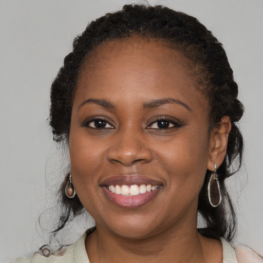 Joyful black young-adult female with long  brown hair and brown eyes