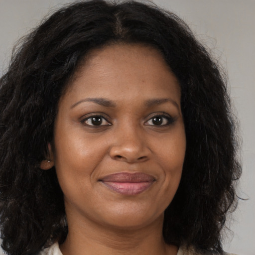 Joyful black young-adult female with long  brown hair and brown eyes