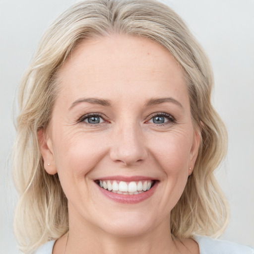 Joyful white adult female with medium  brown hair and blue eyes