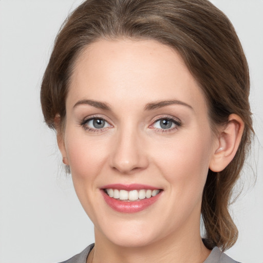 Joyful white young-adult female with medium  brown hair and grey eyes