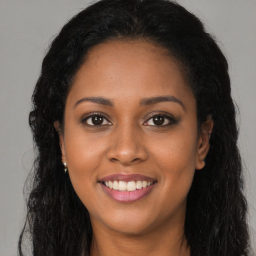 Joyful black young-adult female with long  brown hair and brown eyes