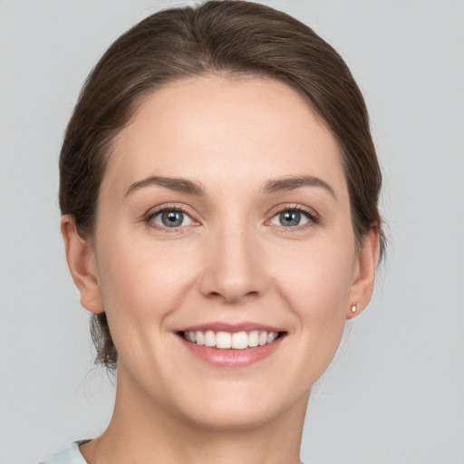 Joyful white young-adult female with medium  brown hair and grey eyes