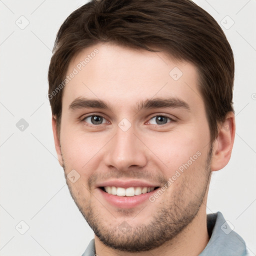 Joyful white young-adult male with short  brown hair and grey eyes